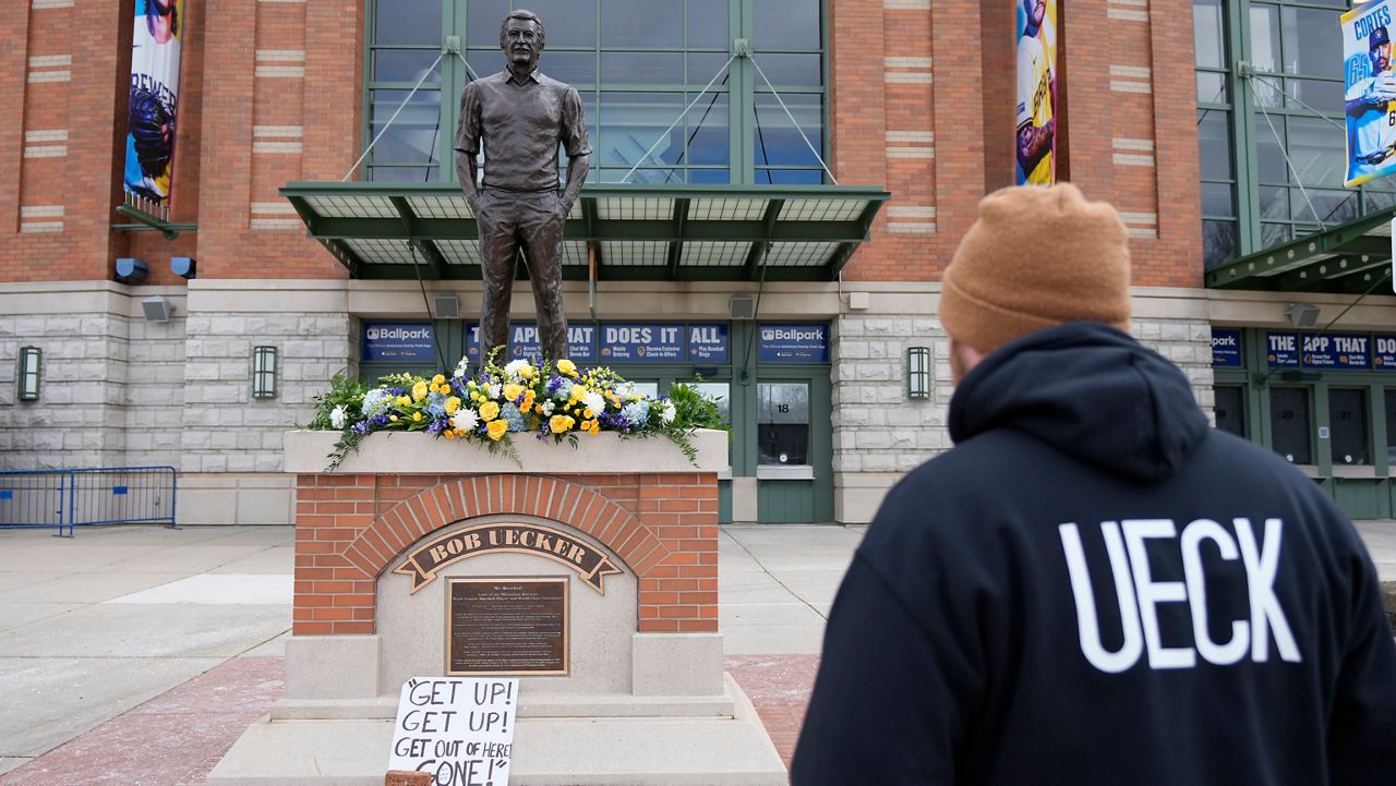 A Milwaukee Brewers fan observes the memorial at the Bob Uecker statue in front of American Family Field prior to a baseball game between the Milwaukee Brewers and the Kansas City Royals on Opening Day Monday, March 31, 2025, in Milwaukee.