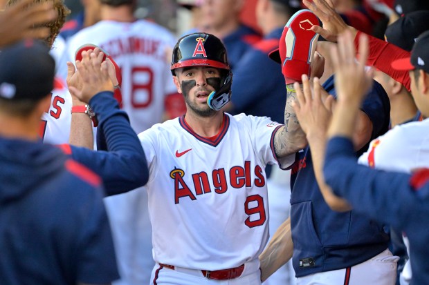 The Angels’ Zach Neto (9) is greeted in the dugout...