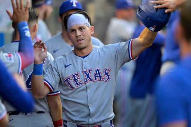 The Texas Rangers’ Sam Haggerty is greeted in the dugout...