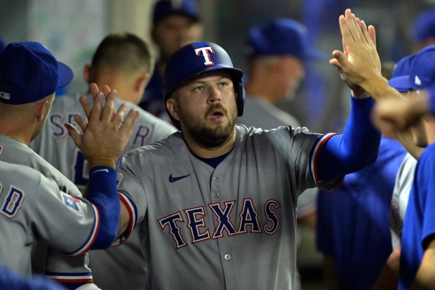 The Texas Rangers’ Jake Burger is greeted in the dugout...
