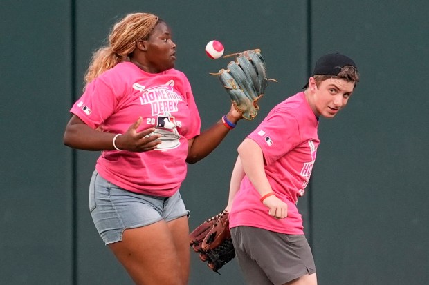Volunteers in the outfield catch a ball hit by Athletics’...