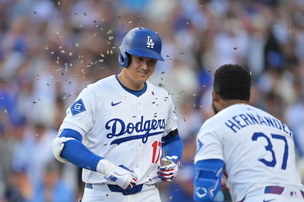 Dodgers star Shohei Ohtani, left, is congratulated by teammate Teoscar...
