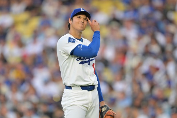 Dodgers pitcher Shohei Ohtani reacts after a base hit by...