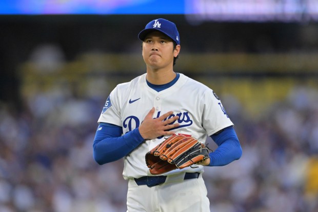 Dodgers starting pitcher Shohei Ohtani reacts after a base hit...