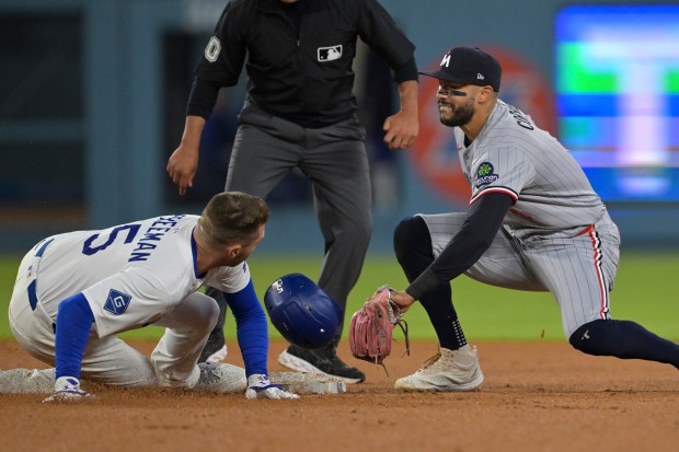 The Dodgers’ Freddie Freeman, left, beats the tag by Minnesota...