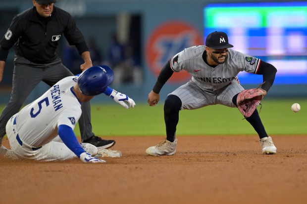 The Dodgers’ Freddie Freeman, left, beats the tag by Minnesota...