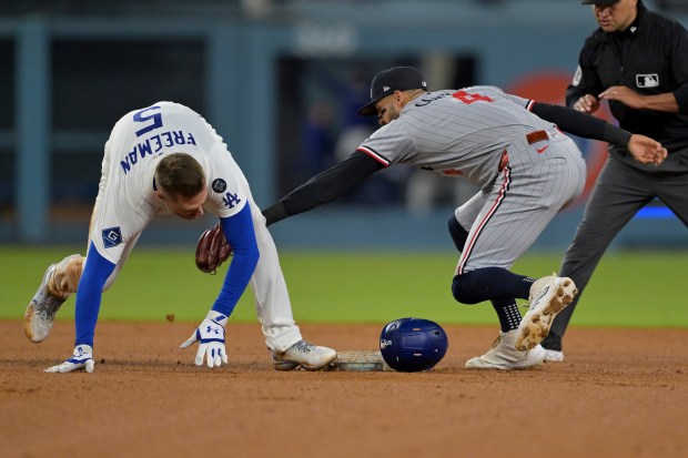 The Dodgers’ Freddie Freeman, left, beats the tag by Minnesota...