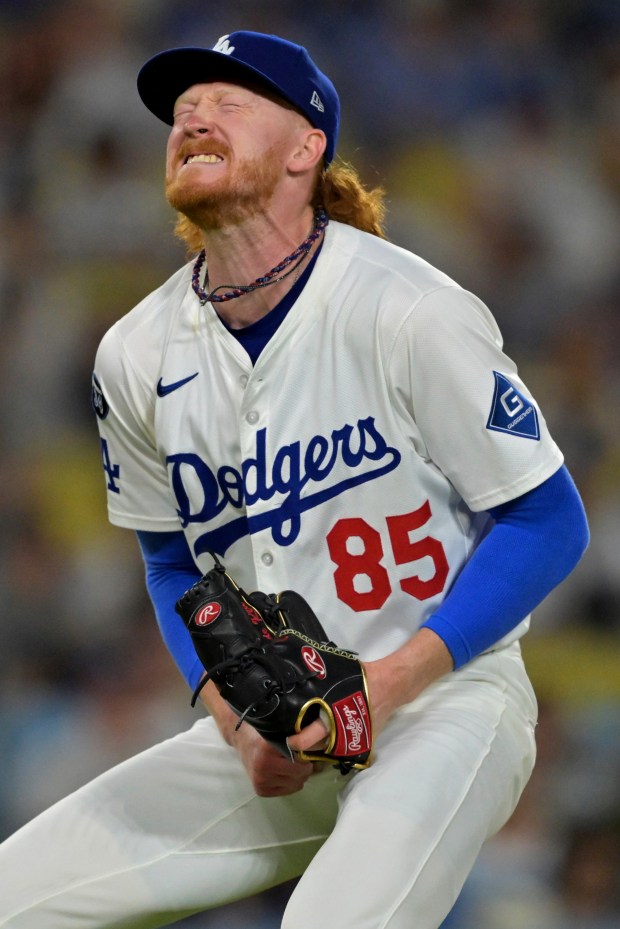 Los Angeles Dodgers starting pitcher Dustin May reacts after giving...