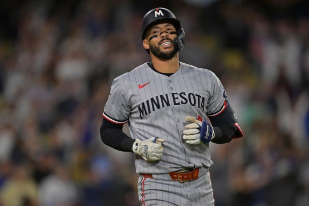 The Minnesota Twins’ Carlos Correa reacts after hitting a long...