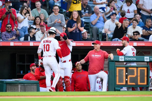 The Angels’ Kevin Newman, left, is greeted by teammates after...