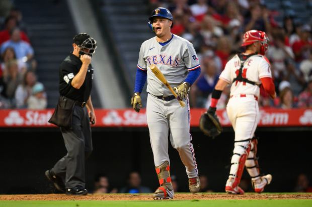The Texas Rangers’ Joc Pederson, center, reacts after striking out...