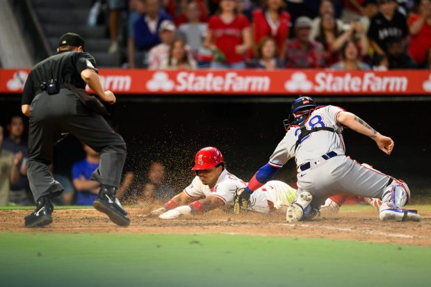 The Angels’ Gustavo Campero, center, slides safely home and scores...
