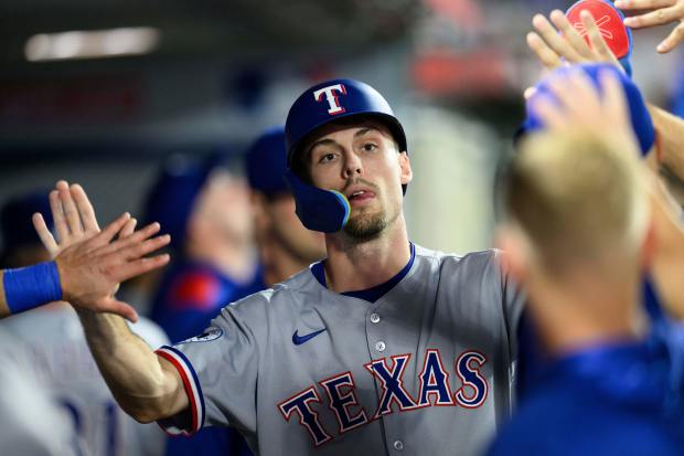 The Texas Rangers’ Evan Carter is greeted by teammates after...