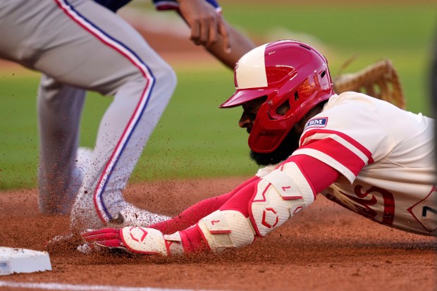 The Angels’ Jo Adell, right, dives back to first base...