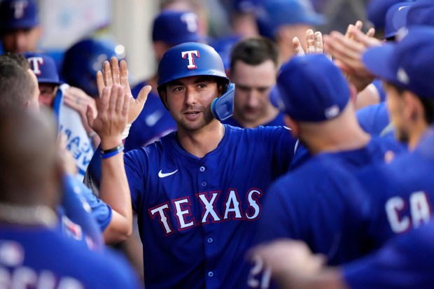 The Texas Rangers’ Kyle Higashioka is congratulated by teammates in...