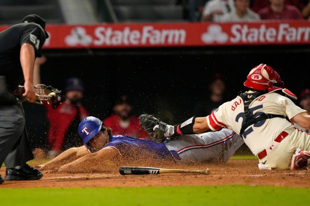 The Texas Rangers’ Josh Smith, center, scores on a single...