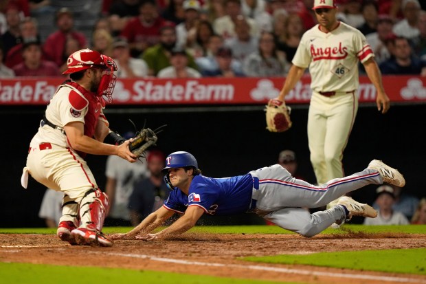 The Texas Rangers’ Josh Smith, center, scores on a single...