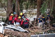 A crew of firefighters from Ciudad Acuna, left, aid in search and rescue efforts near the...