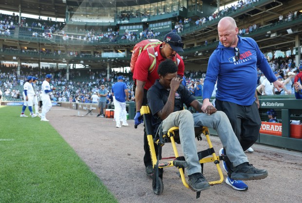 A security worker is transported off the field from being affected by the heat and humidity after a 10-7 Cubs win over the Mariners at Wrigley Field on June 21, 2025. (John J. Kim/Chicago Tribune)