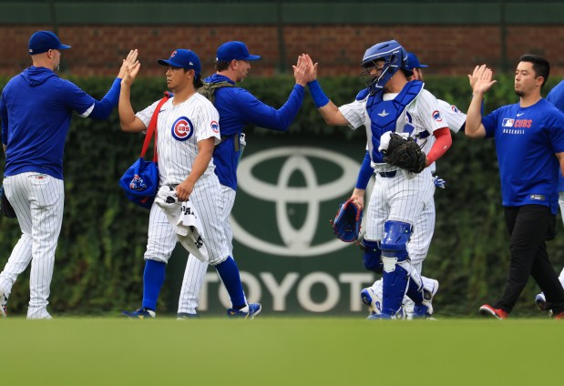 Cubs starter Shota Imanaga, center left, high-fives teammates after warming up for a game against the Red Sox on July 19, 2025, at Wrigley Field. (John J. Kim/Chicago Tribune)