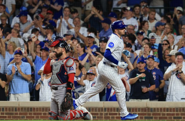 Cubs left fielder Ian Happ, right, crosses the plate past Red Sox catcher Connor Wong after hitting a home run in the eighth inning against the Red Sox on July 19, 2025, at Wrigley Field. (John J. Kim/Chicago Tribune)