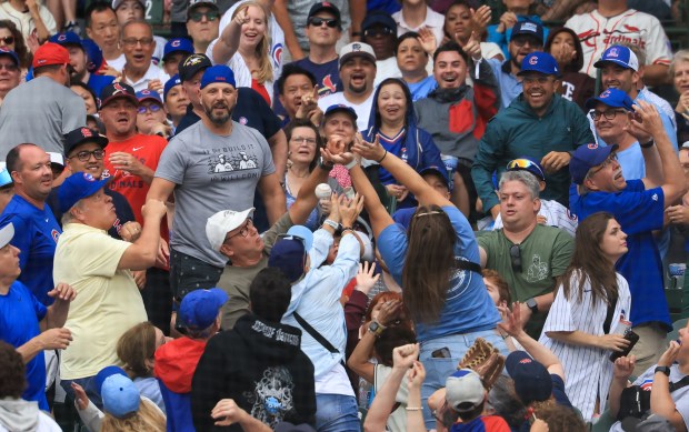 Fans reach for a foul ball in the first inning of a Cubs-Cardinals game at Wrigley Field on July 6, 2025, in Chicago. (John J. Kim/Chicago Tribune)