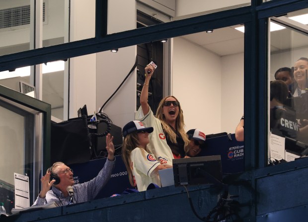 Cubs radio announcer Pat Hughes, left, braces his hands against podcaster Alex Cooper as she is hoisted by friends after singing "Take Me Out to the Ball Game" in the seventh inning of a Cubs-Cardinals game at Wrigley Field on July 6, 2025, in Chicago. (John J. Kim/Chicago Tribune)