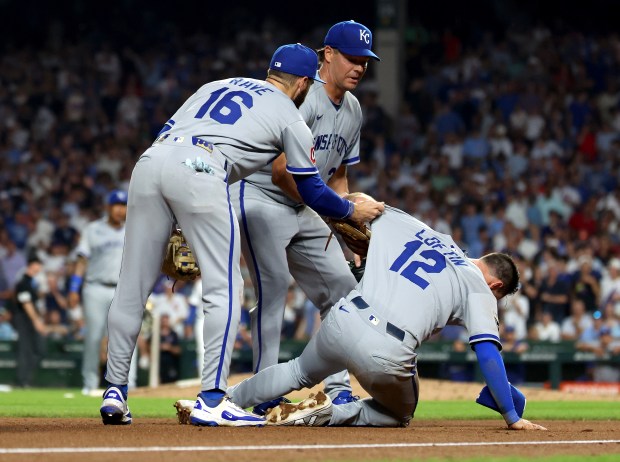Kansas City Royals third baseman Nick Loftin (12) is picked up by teammates John Rave (16) and Rich Hill after Loftin tagged out Chicago Cubs center fielder Pete Crow-Armstrong at third base to end the fifth inning of a game at Wrigley Field in Chicago on July 22, 2025. (Chris Sweda/Chicago Tribune)