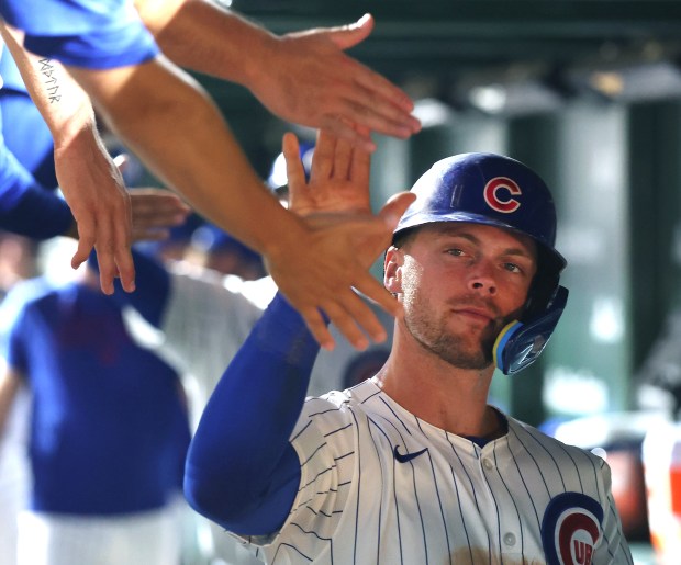 Chicago Cubs second baseman Nico Hoerner is congratulated by his teammates in the dugout after scoring on a sacrifice fly by Carson Kelly in the seventh inning of a game against the Kansas City Royals at Wrigley Field in Chicago on July 22, 2025. (Chris Sweda/Chicago Tribune)
