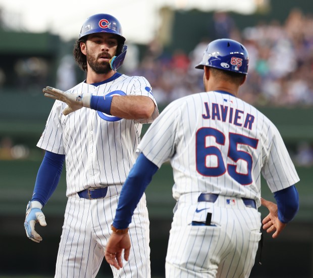 Chicago Cubs shortstop Dansby Swanson celebrates with first base coach Jose Javier (65) after Swanson singled to lead off the second inning of a game against the Kansas City Royals at Wrigley Field in Chicago on July 22, 2025. (Chris Sweda/Chicago Tribune)