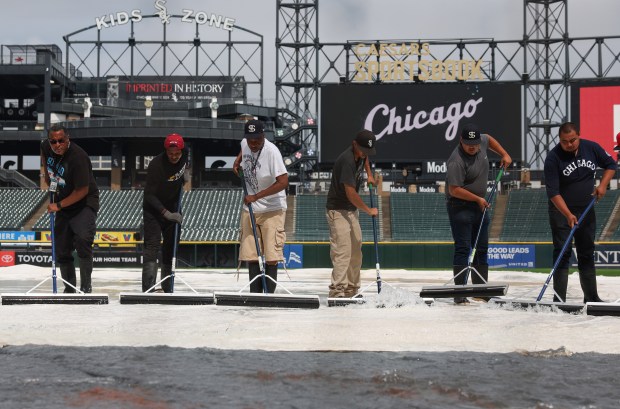Grounds-crew workers clear water off the rain tarp in preparation for a White Sox-Cubs game on July 25, 2025, at Rate Field. (John J. Kim/Chicago Tribune)