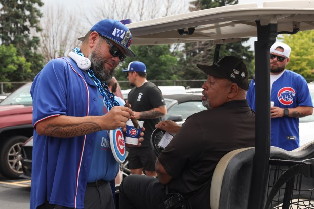 Fausto Cisneros, left, discusses his cigar with a White Sox secuirty worker while tailgating before a White Sox-Cubs game on July 25, 2025, at Rate Field. (John J. Kim/Chicago Tribune)