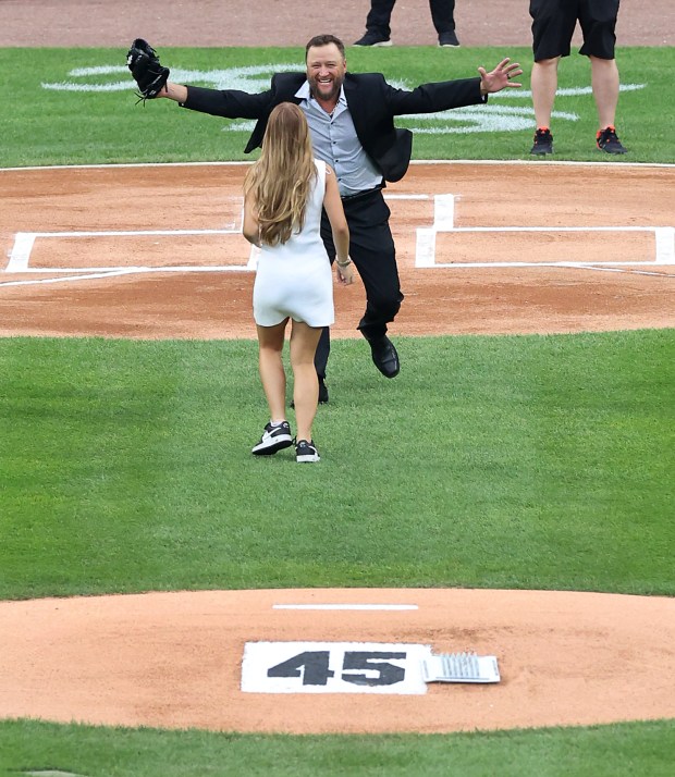 Chicago White Sox great Mark Buehrle runs out to hug his daughter, Brooklyn, after she threw out a ceremonial first pitch on July 11, 2025. The Sox are honoring reliever Bobby Jenks, who died recently, with his number 45, seen at the back of the pitchers mound. (Chris Sweda/Chicago Tribune)