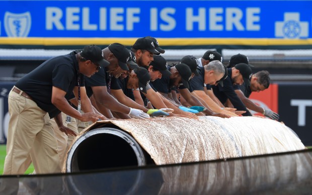 The grounds crew unrolls a rain tarp onto the infield before a White Sox-Phillies game at Rate Field on July 30, 2025, in Chicago. (John J. Kim/Chicago Tribune)