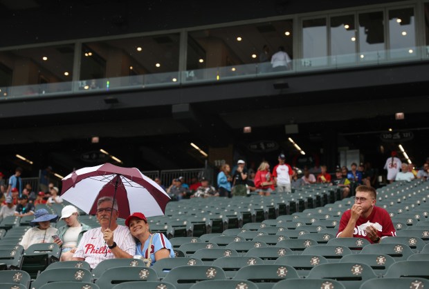 Two Phillies fans sit in their seats under an umbrella as rain begins before a White Sox-Phillies game Wednesday, July 30, 2025, at Rate Field. (John J. Kim/Chicago Tribune)