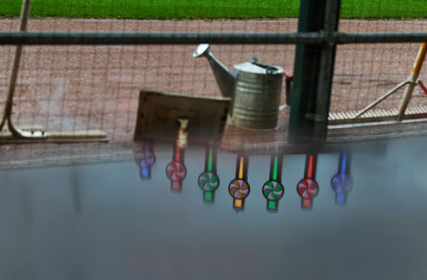 The Rate Field video board pinwheels are reflected in a rain puddle on a dugout railing during a rain delay for a White Sox-Phillies game on July 30, 2025, in Chicago. (John J. Kim/Chicago Tribune)