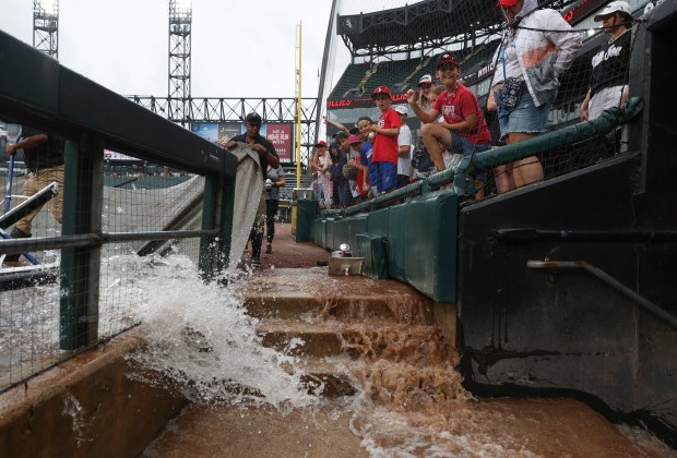 Fans watch as grounds crew workers clear water from the rain tarp into drains in preparation for a delayed White Sox-Phillies game Wednesday, July 30, 2025, at Rate Field. (John J. Kim/Chicago Tribune)