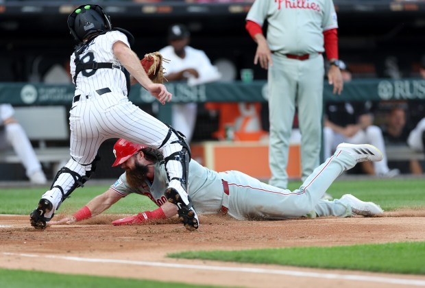 Chicago White Sox catcher Kyle Teel stands by as Philadelphia Phillies center fielder Brandon Marsh slides in to score on a sacrifice fly in the second inning of a game at Rate Field in Chicago on July 29, 2025. (Chris Sweda/Chicago Tribune)