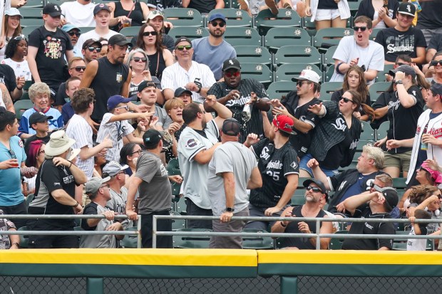 A fan spills his drink as he catches a ball thrown by Chicago White Sox outfielder Luis Robert Jr. (88) in the second inning against the Cleveland Guardians at Rate Field on Sunday, July 13, 2025. (Eileen T. Meslar/Chicago Tribune)