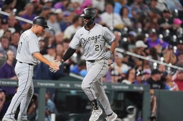 Chicago White Sox third base coach Justin Jirschele, left, congratulates Michael A. Taylor, right, who circles the bases after hitting a two-run home run off Colorado Rockies relief pitcher Ryan Rolison in the ninth inning of a baseball game Saturday, July 5, 2025, in Denver. (AP Photo/David Zalubowski)