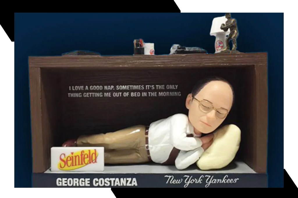 A bobblehead of George Costanza napping under George Steinbrenner's desk.