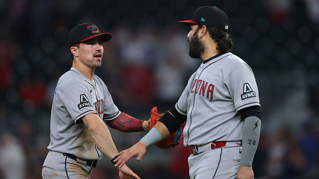 Corbin Carroll #7 of the Arizona Diamondbacks reacts with Eugenio Suarez...