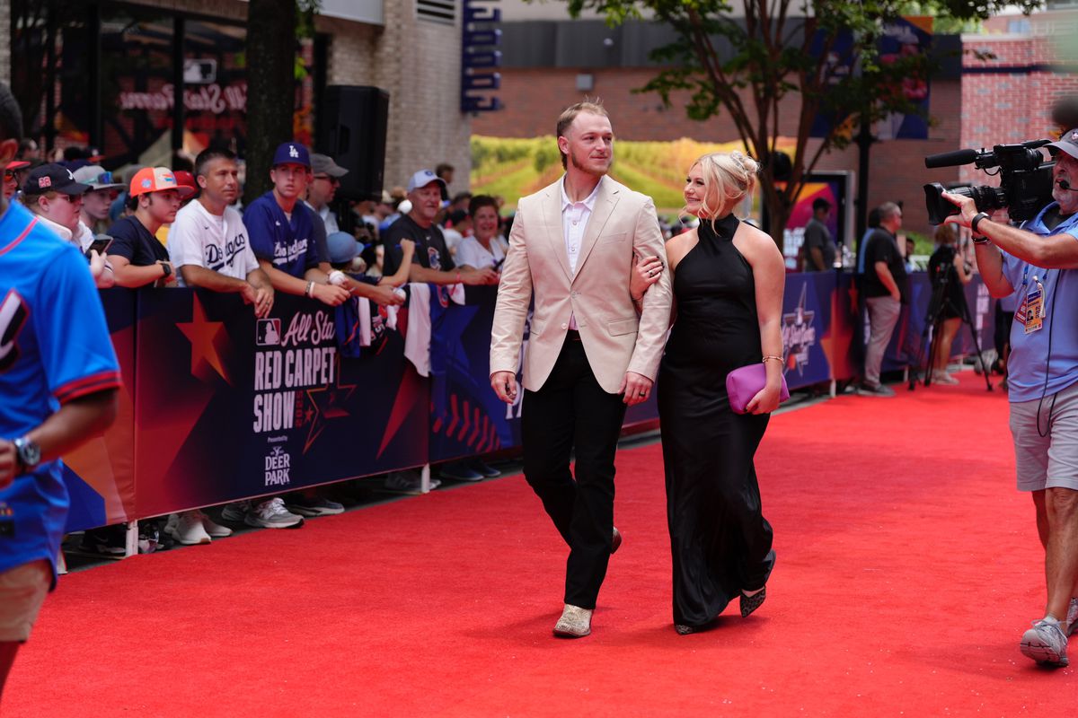 Hunter wears snakeskin cowboys boots, black jeans, and a tan jacket while Sydney wears a black dress and heels.