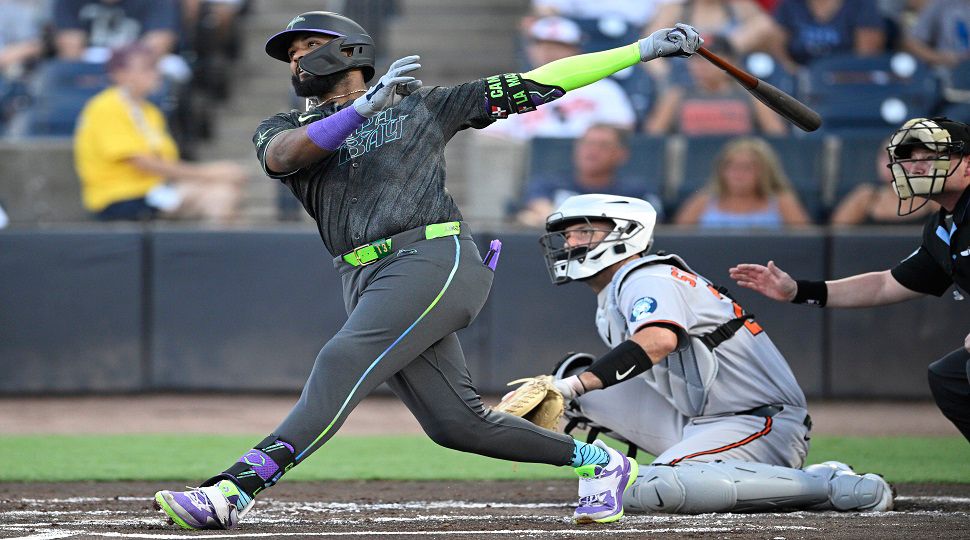 Tampa Bay Rays' Junior Caminero, left, watches the flight of the ball after hitting a three-run home run as Baltimore Orioles catcher Jacob Stallings and home plate umpire Sean Barber, right, look on during the first inning of a baseball game, Friday, July 18, 2025, in Tampa, Fla. (AP Photo/Phelan M. Ebenhack)