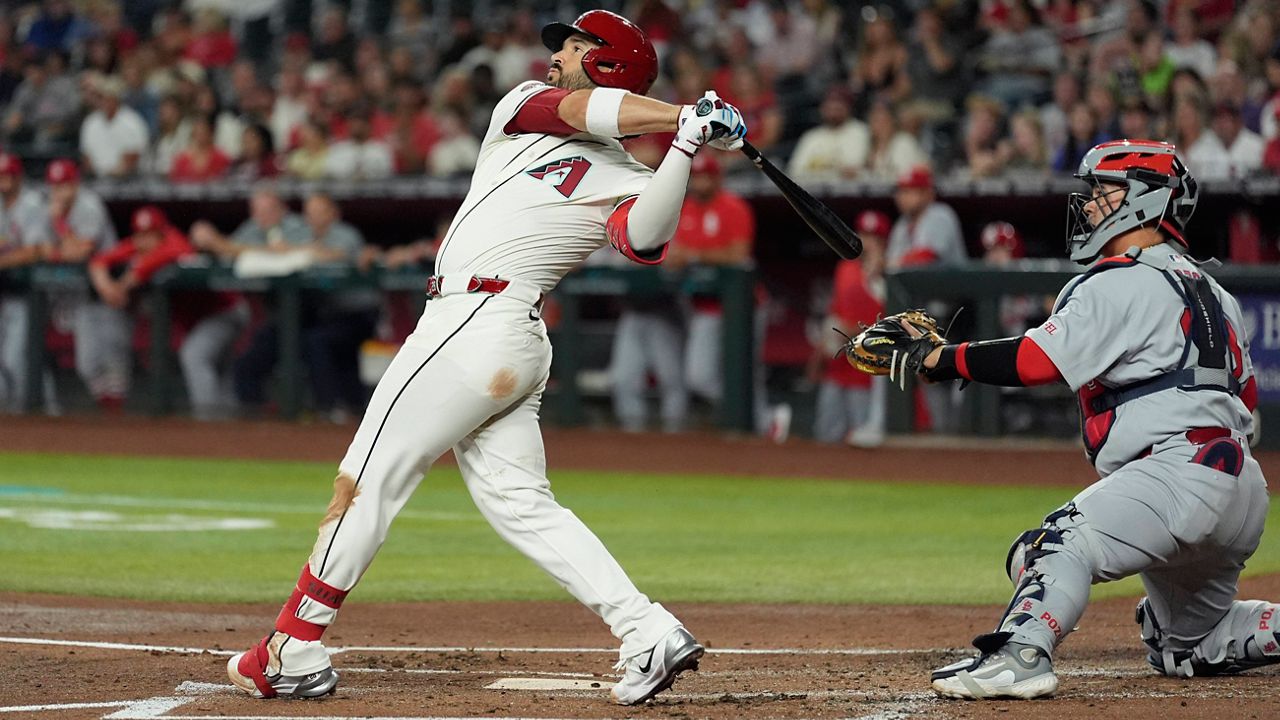 Arizona Diamondbacks' Eugenio Suárez, left, watches the flight of his three-run home run as St. Louis Cardinals catcher Yohel Pozo, right, looks on during the first inning of a baseball game Sunday, July 20, 2025, in Phoenix. (AP Photo/Ross D. Franklin)