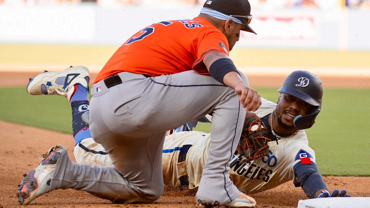 Los Angeles Dodgers' Mookie Betts, right, is tagged out by Houston Astros third baseman Isaac Paredes, left, while trying to stretch for a triple during the seventh inning of a baseball game in Los Angeles, Saturday, July 5, 2025. (AP Photo/Kyusung Gong)