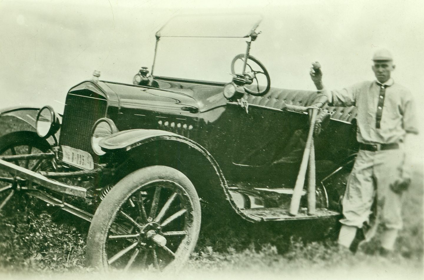 Unidentified ballplayer with Nebraska plates on his car, 1910s.
