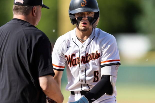 Lincoln-Way West's Conor Essenburg (8) gets fives from the first-base coach after getting a hit against Providence during the Class 4A Providence Sectional final in New Lenox on Friday, May 31, 2024. (Vincent D. Johnson/for the Daily Southtown)