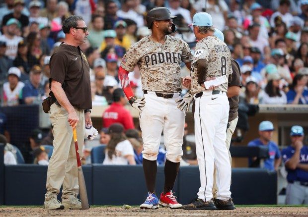 Xander Bogaerts #2 of the San Diego Padres is checked by trainer Mark Rogow (L) and manager Mike Shildt #8 before leaving the game during the tenth inning against the Texas Rangers at Petco Park on Friday, July 4, 2025 in San Diego, CA. (Meg McLaughlin / The San Diego Union-Tribune)