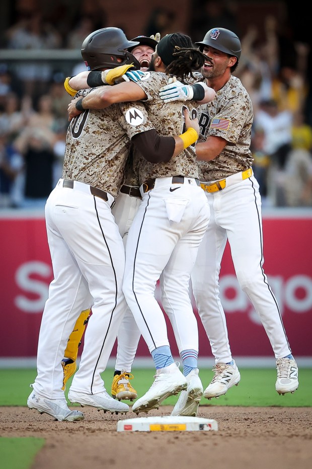 Jake Cronenworth #9 of the San Diego Padres, center, celebrates with teammate after hitting a walk-off single against the Texas Rangers during the tenth inning at Petco Park on Friday, July 4, 2025 in San Diego, CA. (Meg McLaughlin / The San Diego Union-Tribune)